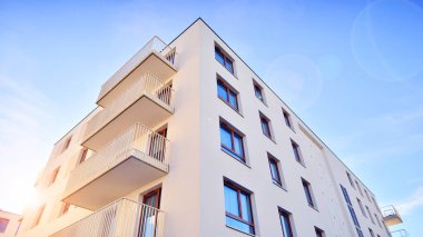 Mavi gökyüzü olan güneşli bir günde modern apartman binaları. Modern bir apartmanın ön cephesi. Gündüz gözüyle çağdaş yerleşim yerinin dış tarafında.. 