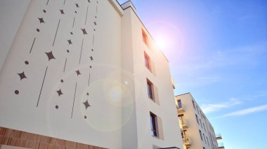 Mavi gökyüzü olan güneşli bir günde modern apartman binaları. Modern bir apartmanın ön cephesi. Gündüz gözüyle çağdaş yerleşim yerinin dış tarafında.. 
