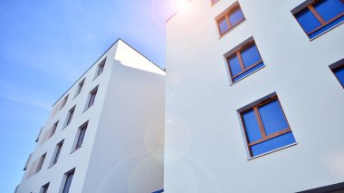 Mavi gökyüzü olan güneşli bir günde modern apartman binaları. Modern bir apartmanın ön cephesi. Gündüz gözüyle çağdaş yerleşim yerinin dış tarafında.. 