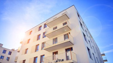 Mavi gökyüzü olan güneşli bir günde modern apartman binaları. Modern bir apartmanın ön cephesi. Gündüz gözüyle çağdaş yerleşim yerinin dış tarafında.. 