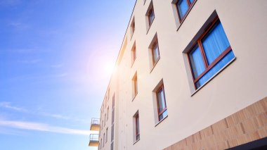 Mavi gökyüzü olan güneşli bir günde modern apartman binaları. Modern bir apartmanın ön cephesi. Gündüz gözüyle çağdaş yerleşim yerinin dış tarafında.. 