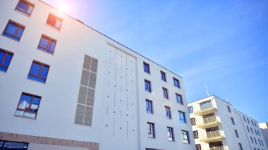 Mavi gökyüzü olan güneşli bir günde modern apartman binaları. Modern bir apartmanın ön cephesi. Gündüz gözüyle çağdaş yerleşim yerinin dış tarafında.. 