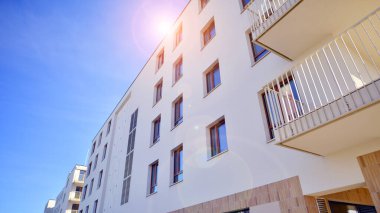 Mavi gökyüzü olan güneşli bir günde modern apartman binaları. Modern bir apartmanın ön cephesi. Gündüz gözüyle çağdaş yerleşim yerinin dış tarafında.. 