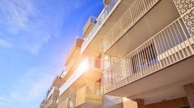 Mavi gökyüzü olan güneşli bir günde modern apartman binaları. Modern bir apartmanın ön cephesi. Gündüz gözüyle çağdaş yerleşim yerinin dış tarafında.. 