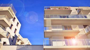 Mavi gökyüzü olan güneşli bir günde modern apartman binaları. Modern bir apartmanın ön cephesi. Gündüz gözüyle çağdaş yerleşim yerinin dış tarafında.. 