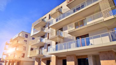 Mavi gökyüzü olan güneşli bir günde modern apartman binaları. Modern bir apartmanın ön cephesi. Gündüz gözüyle çağdaş yerleşim yerinin dış tarafında.. 