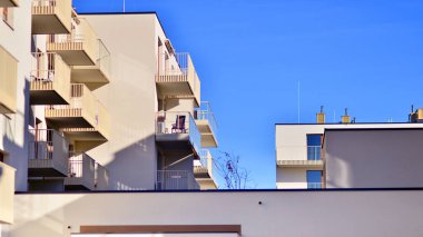 Mavi gökyüzü olan güneşli bir günde modern apartman binaları. Modern bir apartmanın ön cephesi. Gündüz gözüyle çağdaş yerleşim yerinin dış tarafında.. 