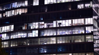 Akşamları daha aydınlık çalışma alanları olan ofis binası. Finans bölgesinde modern, parlak bir gökdelen. Ofiste geç saatlere kadar..