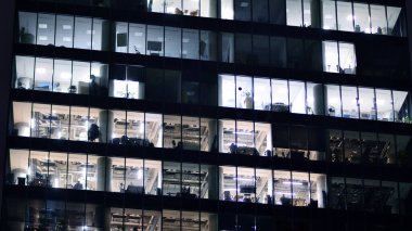 Akşamları daha aydınlık çalışma alanları olan ofis binası. Finans bölgesinde modern, parlak bir gökdelen. Ofiste geç saatlere kadar..