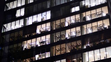 Akşamları daha aydınlık çalışma alanları olan ofis binası. Finans bölgesinde modern, parlak bir gökdelen. Ofiste geç saatlere kadar..