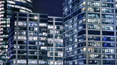 Akşamları daha aydınlık çalışma alanları olan ofis binası. Finans bölgesinde modern, parlak bir gökdelen. Ofiste geç saatlere kadar..