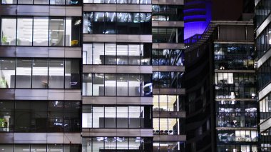 Akşamları daha aydınlık çalışma alanları olan ofis binası. Finans bölgesinde modern, parlak bir gökdelen. Ofiste geç saatlere kadar..