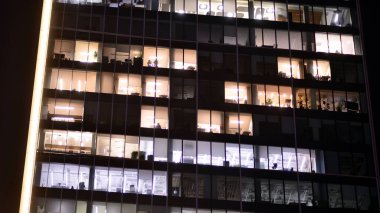 Akşamları daha aydınlık çalışma alanları olan ofis binası. Finans bölgesinde modern, parlak bir gökdelen. Ofiste geç saatlere kadar..