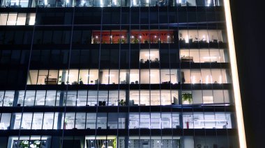 Akşamları daha aydınlık çalışma alanları olan ofis binası. Finans bölgesinde modern, parlak bir gökdelen. Ofiste geç saatlere kadar..