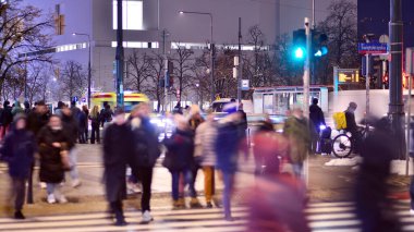 Varşova, Polonya. 22 Kasım 2024. Büyük bir şehrin caddesi. Farklı yaşlarda insanlar karşıdan karşıya geçiyor. Şehir caddesi manzarası sakinleri, turistler ve modern binalar. Şehir merkezinde bir akşam.