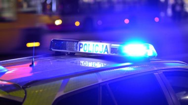 Varşova, Polonya. 22 Kasım 2024. Devriye gezen bir polis arabası ve gece sokakta mavi ışıklar..