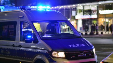 Varşova, Polonya. 22 Kasım 2024. Devriye gezen bir polis arabası ve gece sokakta mavi ışıklar..