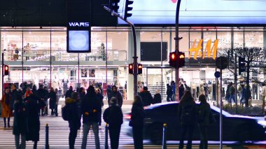 Varşova, Polonya. 22 Kasım 2024. Büyük bir şehrin caddesi. Farklı yaşlarda insanlar karşıdan karşıya geçiyor. Şehir caddesi manzarası sakinleri, turistler ve modern binalar. Şehir merkezinde bir akşam.