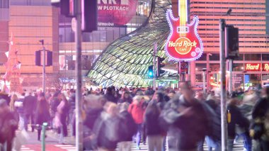 Varşova, Polonya. 22 Kasım 2024. Büyük bir şehrin caddesi. Farklı yaşlarda insanlar karşıdan karşıya geçiyor. Şehir caddesi manzarası sakinleri, turistler ve modern binalar. Şehir merkezinde bir akşam.