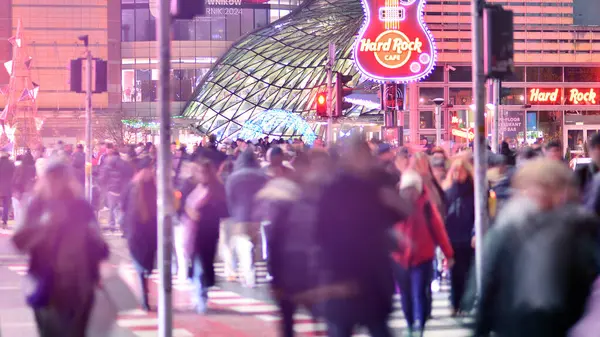 Varşova, Polonya. 22 Kasım 2024. Büyük bir şehrin caddesi. Farklı yaşlarda insanlar karşıdan karşıya geçiyor. Şehir caddesi manzarası sakinleri, turistler ve modern binalar. Şehir merkezinde bir akşam.