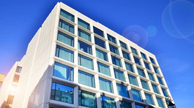 Modern bir otel binasında büyük cam pencereler. Modern şehir mimarisi. Beton duvar panellerinde geniş cam parçaları var..