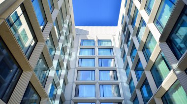 Modern bir otel binasında büyük cam pencereler. Modern şehir mimarisi. Beton duvar panellerinde geniş cam parçaları var..