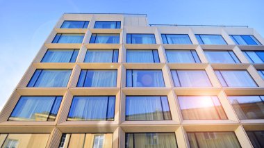 Modern bir otel binasında büyük cam pencereler. Modern şehir mimarisi. Beton duvar panellerinde geniş cam parçaları var..