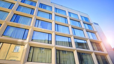 Modern bir otel binasında büyük cam pencereler. Modern şehir mimarisi. Beton duvar panellerinde geniş cam parçaları var..