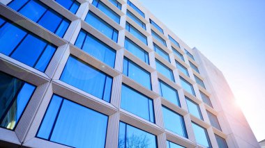 Modern bir otel binasında büyük cam pencereler. Modern şehir mimarisi. Beton duvar panellerinde geniş cam parçaları var..