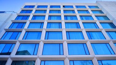 Modern bir otel binasında büyük cam pencereler. Modern şehir mimarisi. Beton duvar panellerinde geniş cam parçaları var..