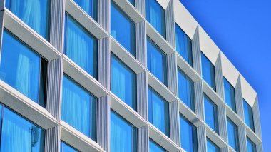 Modern bir otel binasında büyük cam pencereler. Modern şehir mimarisi. Beton duvar panellerinde geniş cam parçaları var..