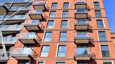 Modern Avrupa apartmanı. Mimarlık ve gayrimenkul, panoramik pencereli bir apartman. Mavi gökyüzü arka planına sahip modern kompleks.