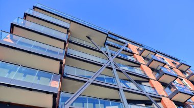 Modern Avrupa apartmanı. Mimarlık ve gayrimenkul, panoramik pencereli bir apartman. Mavi gökyüzü arka planına sahip modern kompleks.