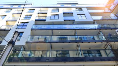 Modern Avrupa apartmanı. Mimarlık ve gayrimenkul, panoramik pencereli bir apartman. Mavi gökyüzü arka planına sahip modern kompleks.