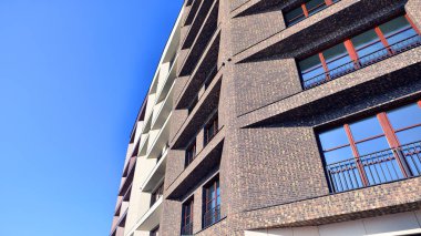 Modern Avrupa apartmanı. Mimarlık ve gayrimenkul, panoramik pencereli bir apartman. Mavi gökyüzü arka planına sahip modern kompleks.