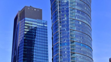 Binanın şeffaf yüzüyle cam bina ve mavi gökyüzü. Yapısal cam duvar mavi gökyüzünü yansıtıyor. Soyut modern mimari parçası. Çağdaş mimari arka plan.