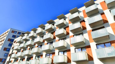 Şehirde simetrik modern mimarisi olan bir apartman. Güneşli bir günde modern apartman binası. Modern bir apartmanın ön cephesi. Alt görünüm. 