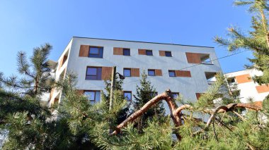 Şehirde simetrik modern mimarisi olan bir apartman. Güneşli bir günde modern apartman binası. Modern bir apartmanın ön cephesi. Alt görünüm. 