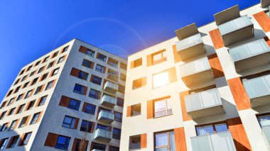 Şehirde simetrik modern mimarisi olan bir apartman. Güneşli bir günde modern apartman binası. Modern bir apartmanın ön cephesi. Alt görünüm. 