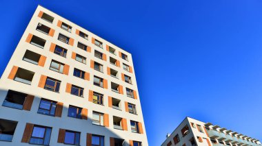 Şehirde simetrik modern mimarisi olan bir apartman. Güneşli bir günde modern apartman binası. Modern bir apartmanın ön cephesi. Alt görünüm. 