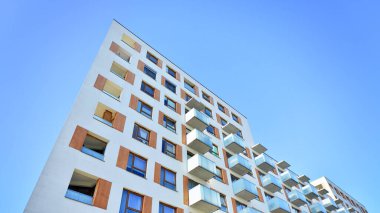 Şehirde simetrik modern mimarisi olan bir apartman. Güneşli bir günde modern apartman binası. Modern bir apartmanın ön cephesi. Alt görünüm. 