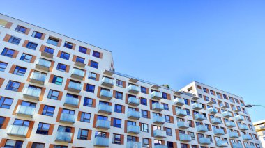 Şehirde simetrik modern mimarisi olan bir apartman. Güneşli bir günde modern apartman binası. Modern bir apartmanın ön cephesi. Alt görünüm. 