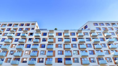 Şehirde simetrik modern mimarisi olan bir apartman. Güneşli bir günde modern apartman binası. Modern bir apartmanın ön cephesi. Alt görünüm. 