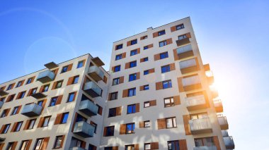 Şehirde simetrik modern mimarisi olan bir apartman. Güneşli bir günde modern apartman binası. Modern bir apartmanın ön cephesi. Alt görünüm. 