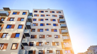 Şehirde simetrik modern mimarisi olan bir apartman. Güneşli bir günde modern apartman binası. Modern bir apartmanın ön cephesi. Alt görünüm. 