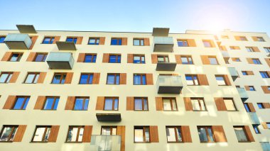 Şehirde simetrik modern mimarisi olan bir apartman. Güneşli bir günde modern apartman binası. Modern bir apartmanın ön cephesi. Alt görünüm. 