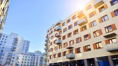 Şehirde simetrik modern mimarisi olan bir apartman. Güneşli bir günde modern apartman binası. Modern bir apartmanın ön cephesi. Alt görünüm. 