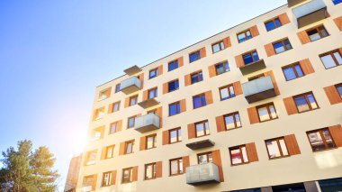 Şehirde simetrik modern mimarisi olan bir apartman. Güneşli bir günde modern apartman binası. Modern bir apartmanın ön cephesi. Alt görünüm. 