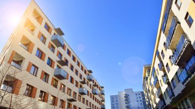 Şehirde simetrik modern mimarisi olan bir apartman. Güneşli bir günde modern apartman binası. Modern bir apartmanın ön cephesi. Alt görünüm. 