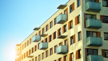 Şehirde simetrik modern mimarisi olan bir apartman. Güneşli bir günde modern apartman binası. Modern bir apartmanın ön cephesi. Alt görünüm. 